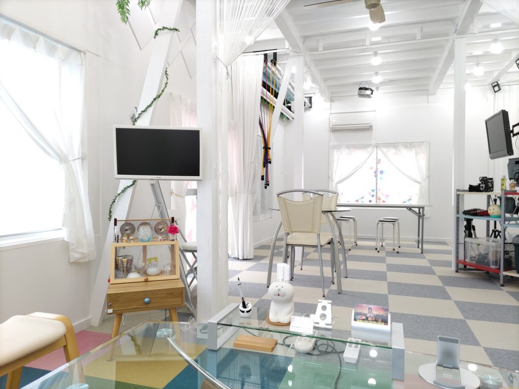 スタジオ内の広いスペースに配置されたガラスのテーブルとシンプルな椅子。